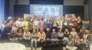 Iso joukko ihmisiä istuu ja seisoo ryhmäkuvassa.