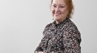 Nainen kirjavassa puserossa pöydän ääressä