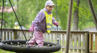 Ulkovaatteisiin pukeutunut lapsi keinussa