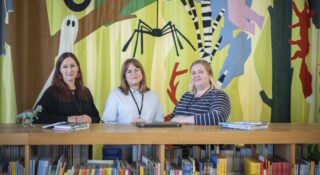 Kolme naista seisoo pöydän ääressä