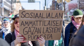 Kaksi naista mielenosoituksessa kyltin kanssa