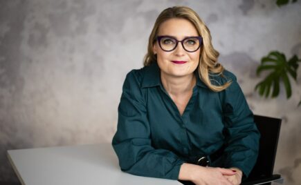 Pitkähiuksinen silmälasipäinen nainen vihreässä puserossa
