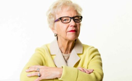 Vaaleahiuksinen nainen keltaisessa puserossa.