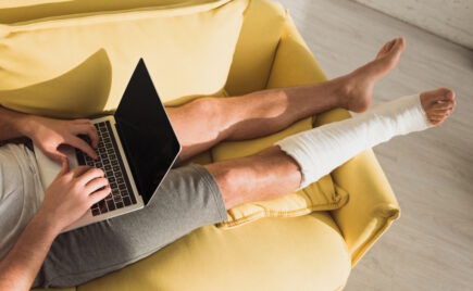 Mies makaa sohvalla jalka kipsissä