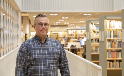 Silmälasipäinen mies ruudullisessa paitapuserossa.