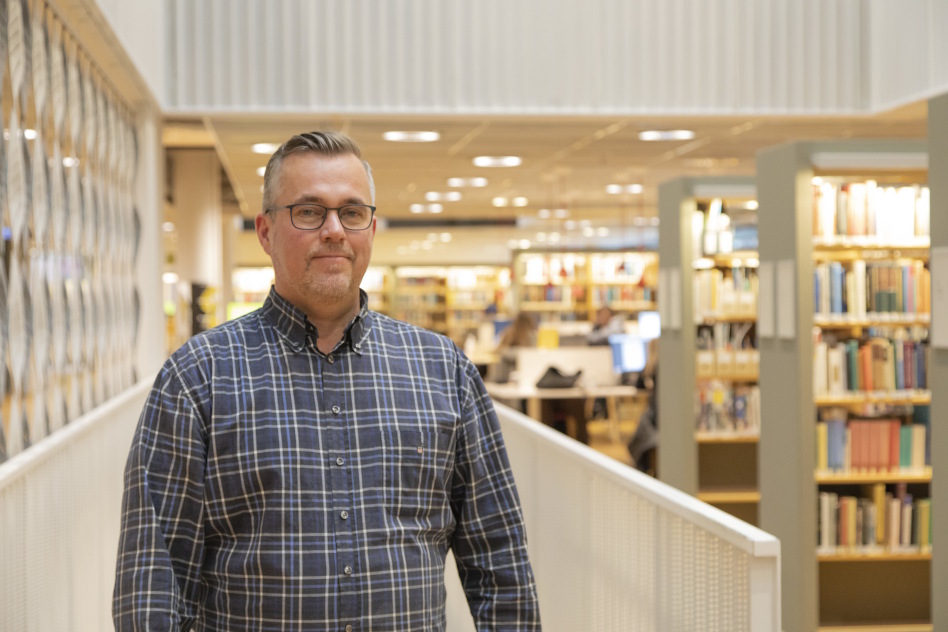 Silmälasipäinen mies ruudullisessa paitapuserossa.