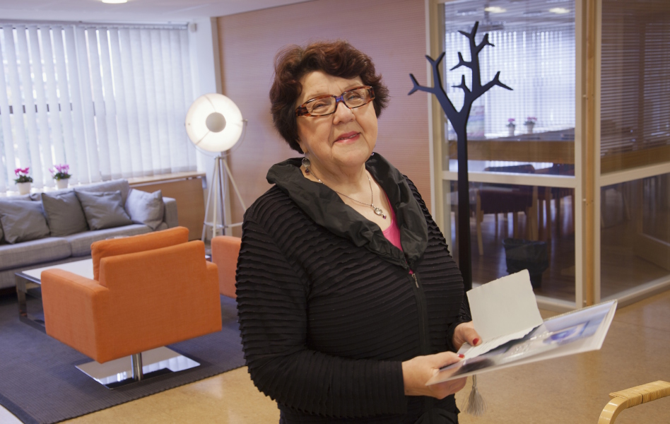 Tummahiuksinen keski-ikäinen nainen seisoo huoneessa