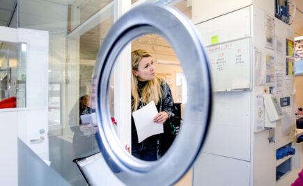 Vaaleahiuksinen nainen näkyy pyöreän ikkunan takaa