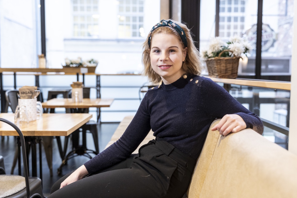 Vaaleatukkainen nainen istuu sohvalla