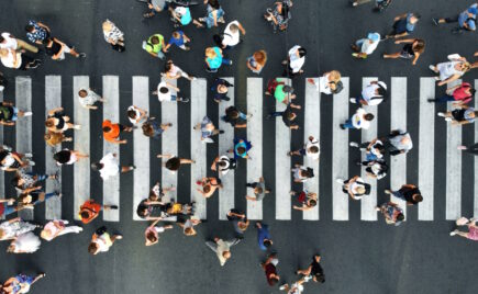 Ylhäältäpäin kuvattu joukko ihmisiä, jotka kulkevat suojatiellä