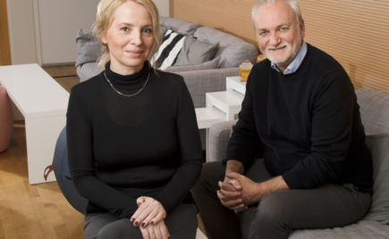 Mies ja nainen mustissa puseroissa istuvat sohvalla