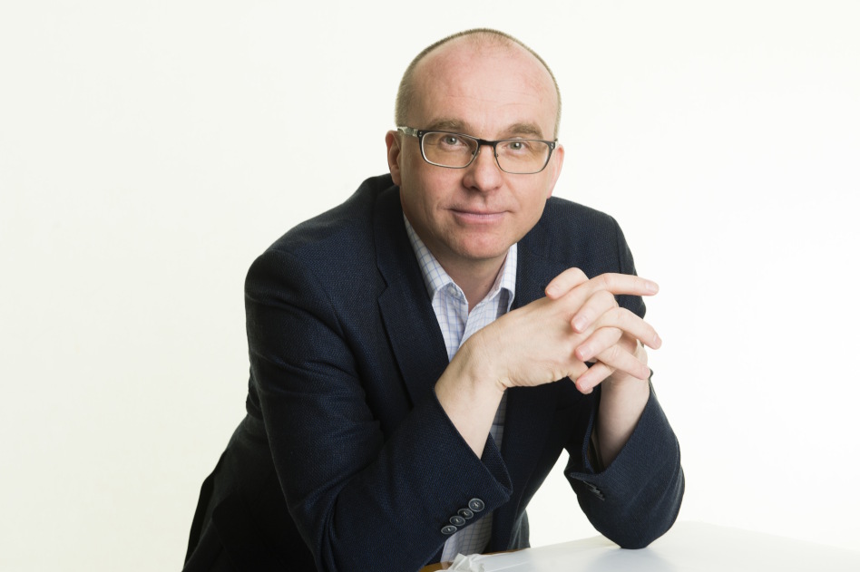 Mies istuu sormet ristissä