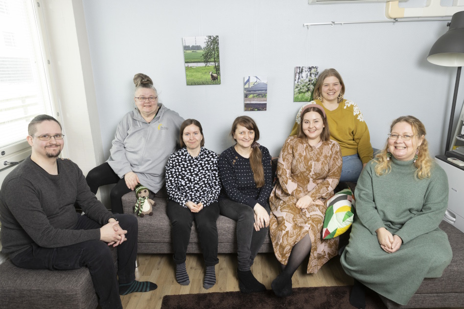 Ryhmä miehiä ja naisia istuu sohvalla.