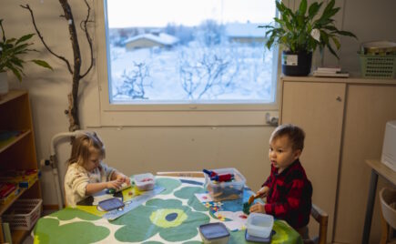 Kaksi lasta leikkii pöydän ääressä