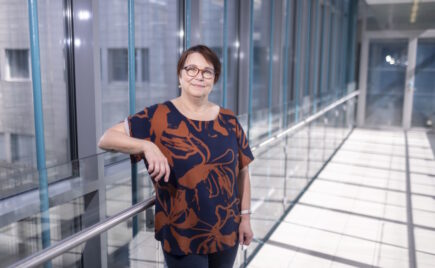 Silmälasipäinen nainen lasiseinän edessä