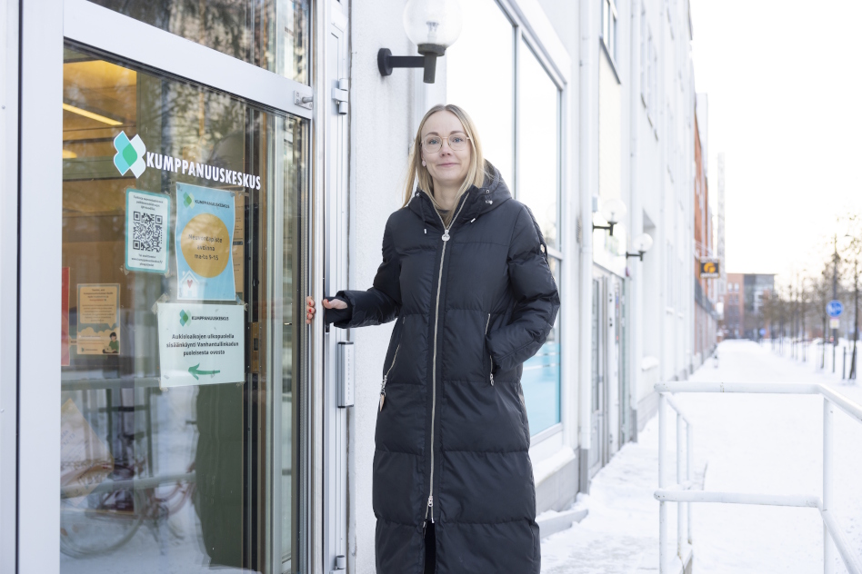 Vaaleahiuksinen nainen toppatakissa oven edessä ulkona