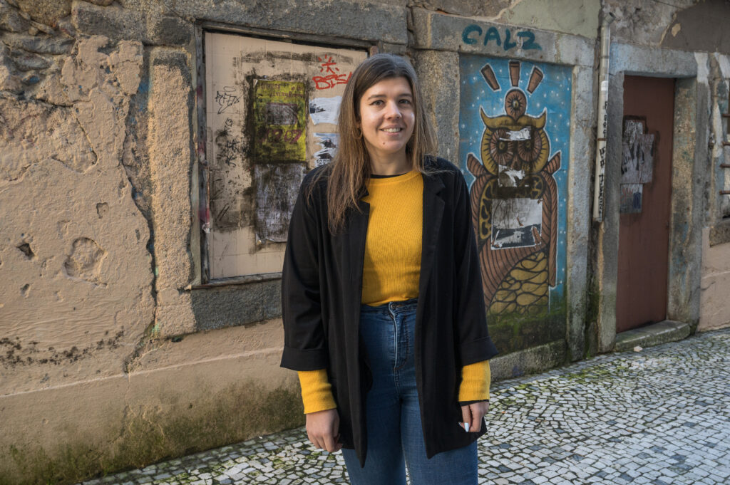 Tummahiuksinen nainen seisoo värikkään muurin edessä