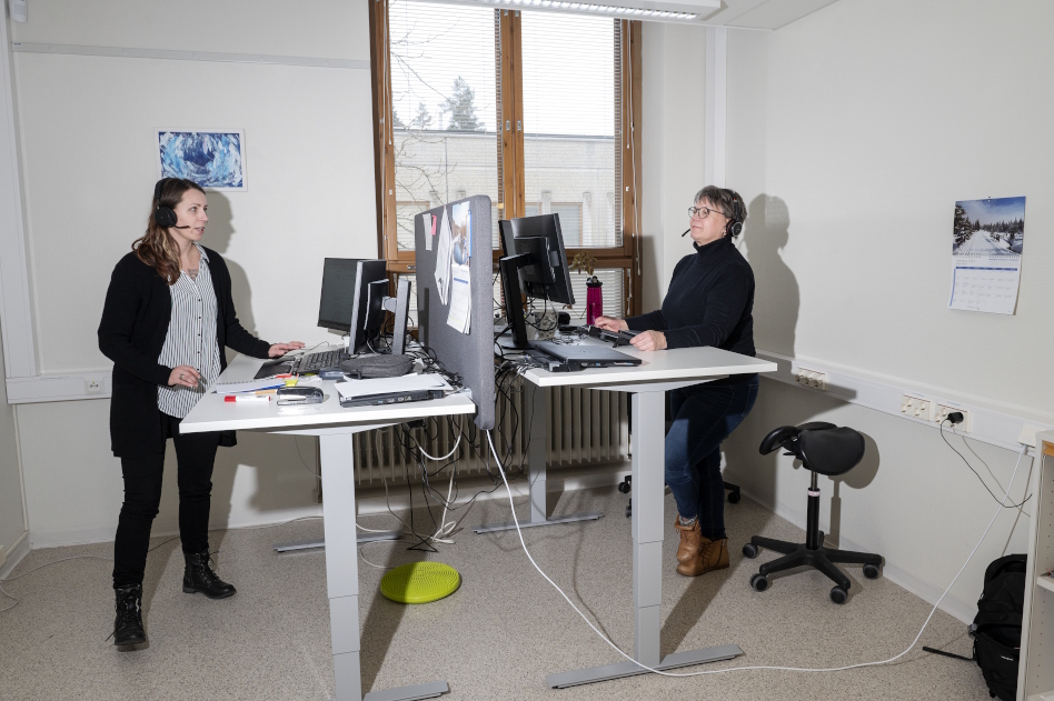 Kaksi naista seisoo vastakkain olevien työpöytien ääressä