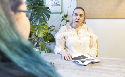 Nainen vaaleassa paidassa istuu työpöydän ääressä.