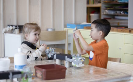 Kaksi lasta leikkii pöydän äärellä