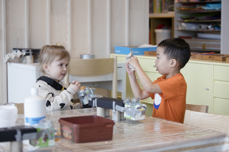 Kaksi lasta leikkii pöydän äärellä