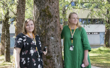 Kaksi naista seisoo puun vieressä