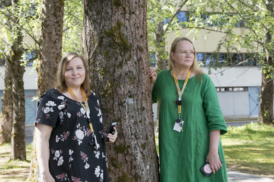 Kaksi naista seisoo puun vieressä
