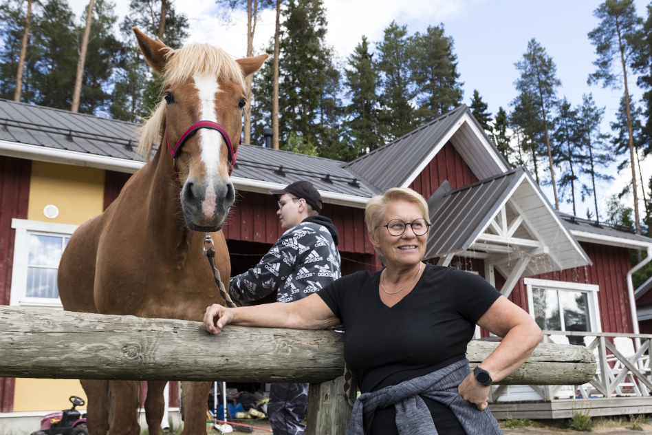 Kaksi naista seisoo rakennuksen edessä hevosen kanssa.