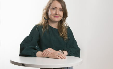 Nainen vihreässä paidassa seisoo pöydän ääressä