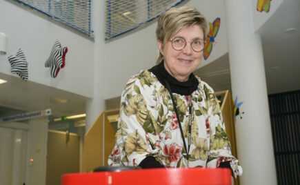 Silmälasipäinen naineen istuu pöydän edessä