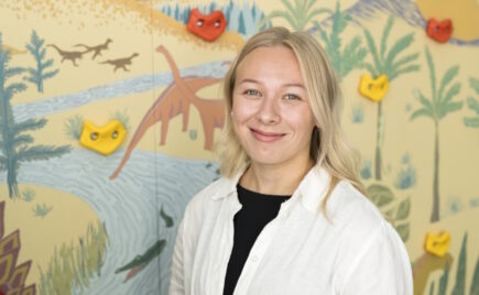 Vaaleahiuksinen nainen eläinaiheisen seinän edessä