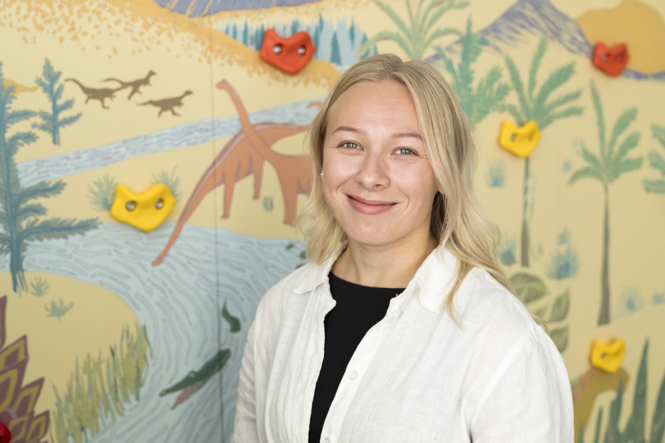 Vaaleahiuksinen nainen eläinaiheisen seinän edessä