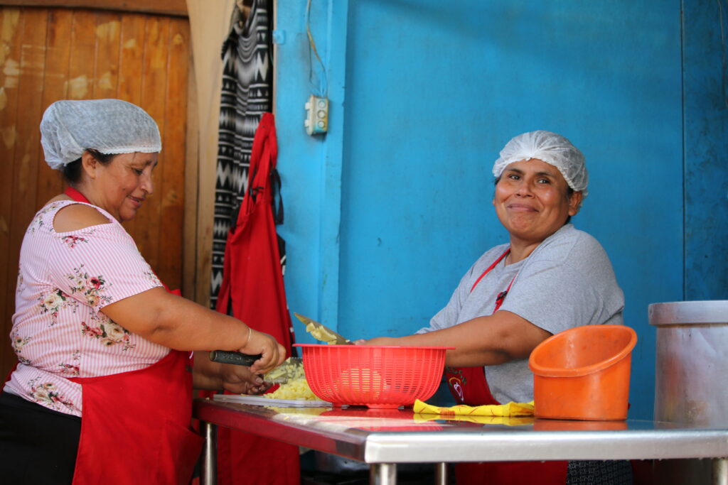Kaksi naista yksinkertaisessa keittiössä suojahuput päässä