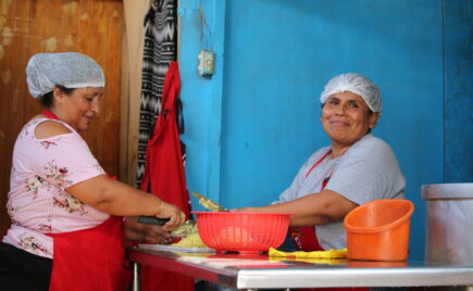 Kaksi naista yksinkertaisessa keittiössä suojahuput päässä
