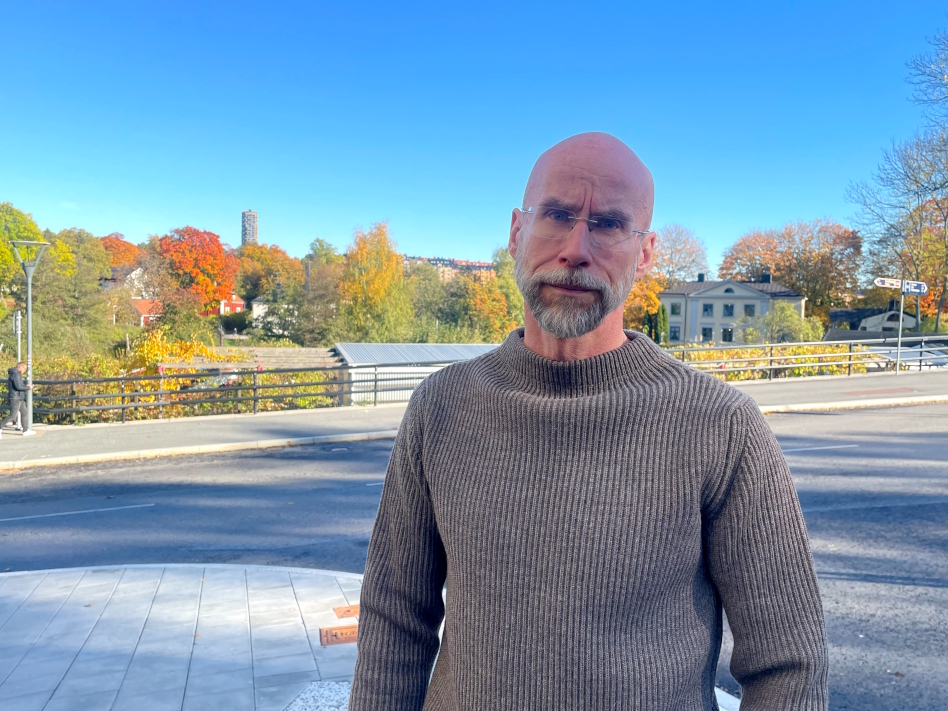 Kaljupäinen mies harmaassa villapaidassa