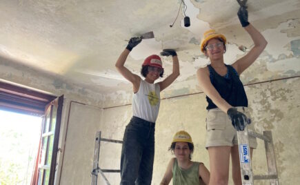 Kolme naista korjaa talon kattoa sisäpuolelta