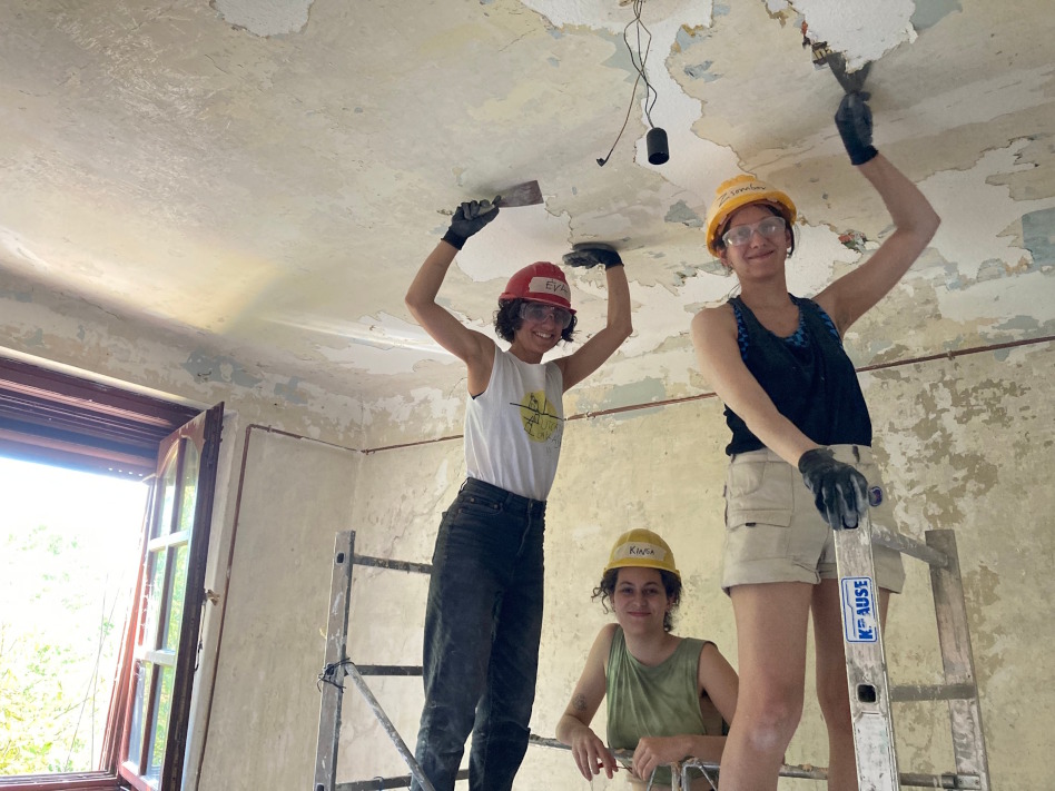 Kolme naista korjaa talon kattoa sisäpuolelta