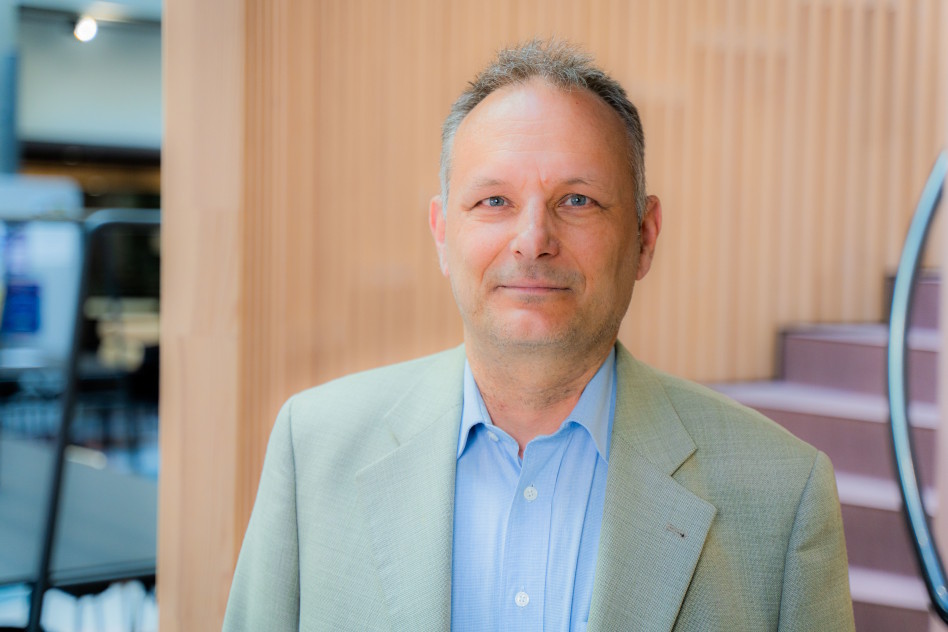 Lähikuva miehestä vaaleassa puvuntakissa