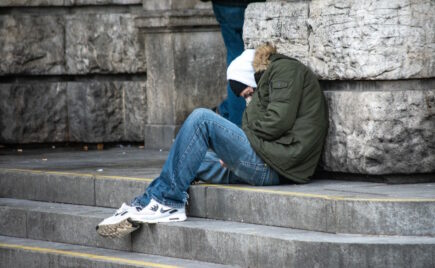 Poika huppu päässä nukkuu istualtaan portailla