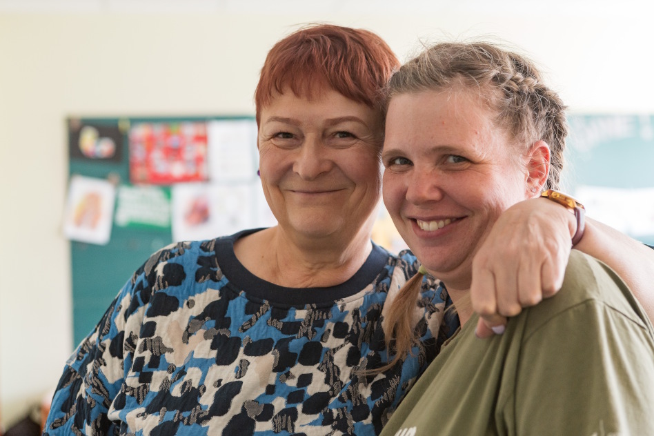 Kaksi hymyilevää naista halaa