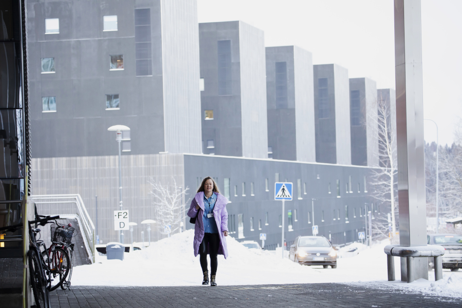 Nainen isojen kerrostalojen edessä.