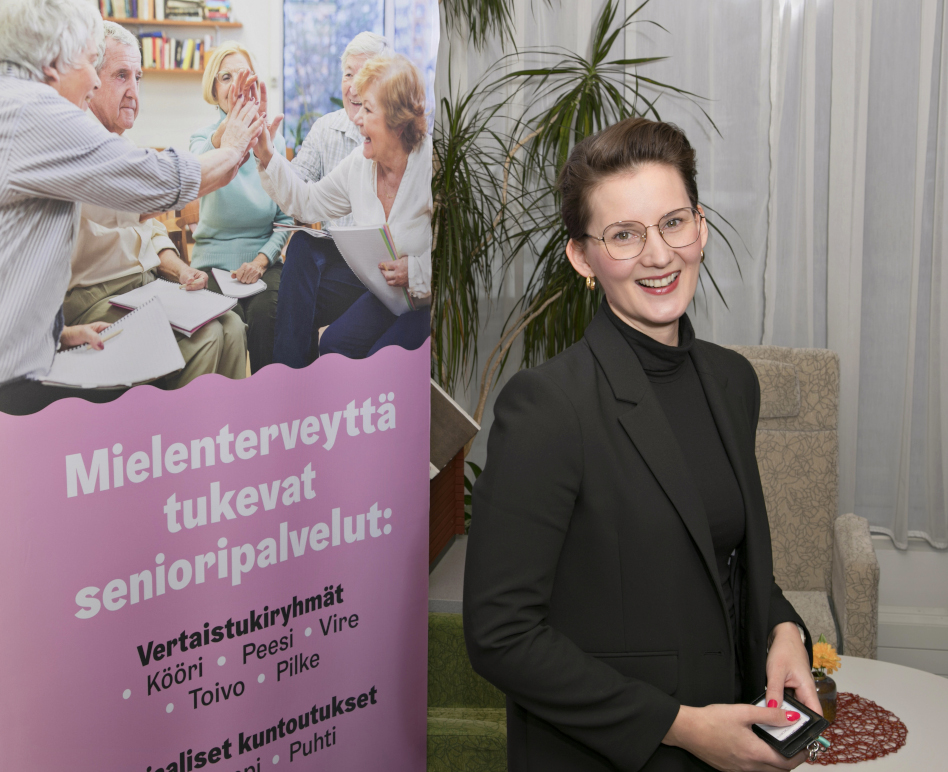 Nainen seisoo värikkään julkisteen edessä