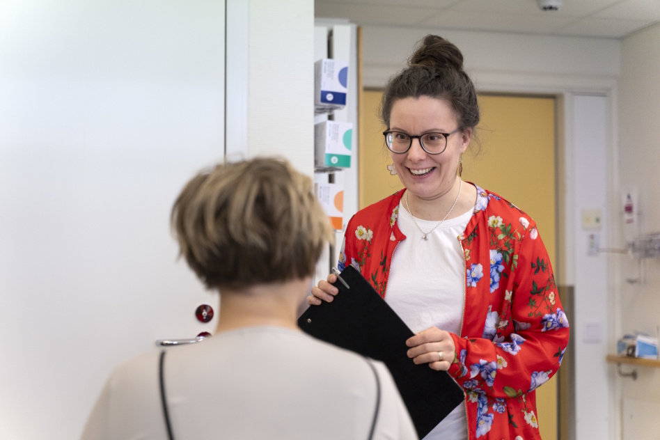 Punapaitainen nainen toisen naisen edessä kirja kädessään