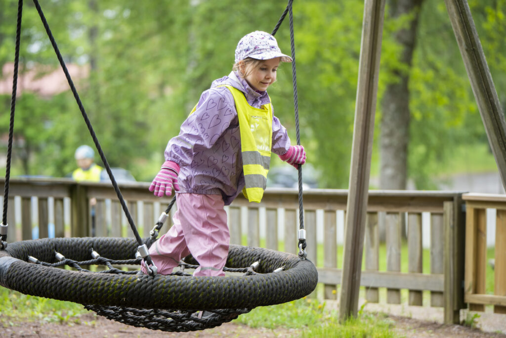 Ulkovaatteisiin pukeutunut lapsi keinussa