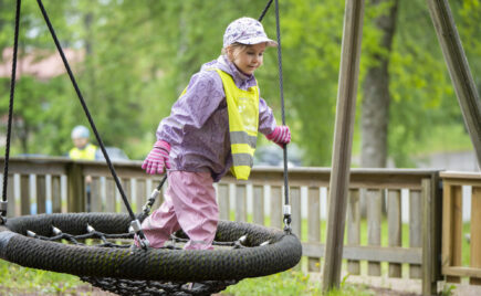 Ulkovaatteisiin pukeutunut lapsi keinussa