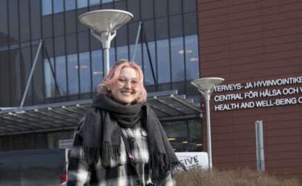 Punatukkainen tyttö seisoo toimistorakennuksen edessä.