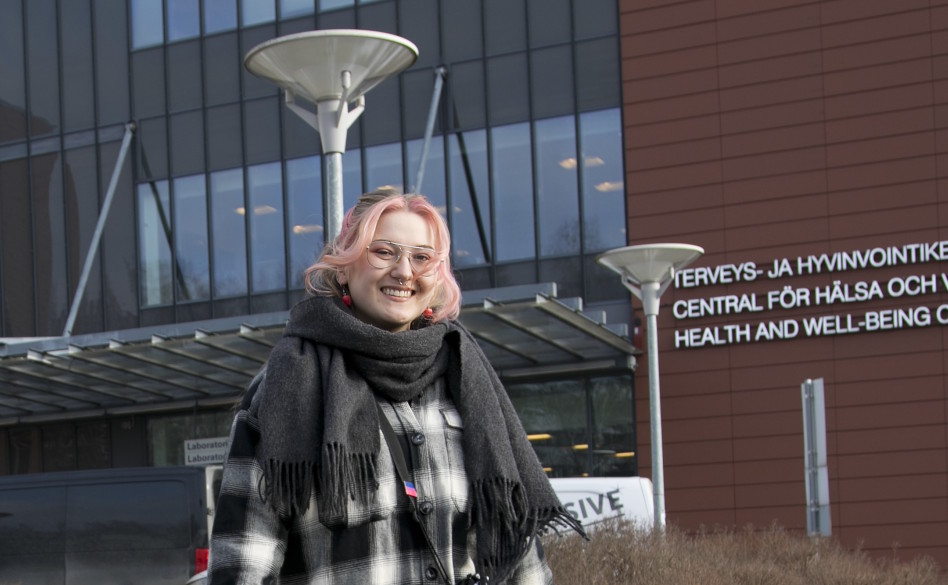 Punatukkainen tyttö seisoo toimistorakennuksen edessä.