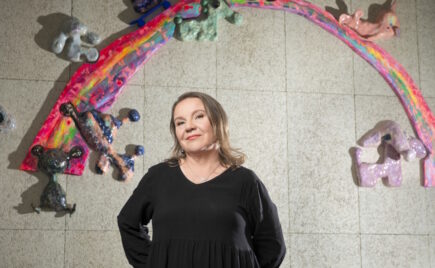 Mustapuseroinen nainen seisoo seinän edessä