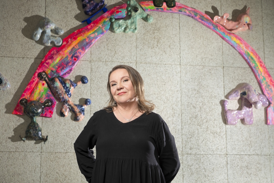 Mustapuseroinen nainen seisoo seinän edessä