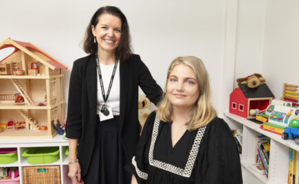 Kaksi naista vierekkäin, toinen istuu, toinen seisoo